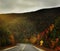 The road running among the mountains overgrown with autumnal bright forest and dramatic sky.White Mountain National Park. USA. New