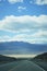 Road running towards mountains. Bright blue cloudy sky