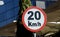 A road sign of 20 KMH twenty Kilometers per hour speed limit in the slow lane near gateway, restaurants and cafes, Prohibitory