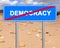 Road sign. Democracy termination location mark opposite the stony desert landscape. Word democracy crossed out with a red line