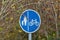 Road sign denoting the cycle lane and pedestrian lane situated in a rural area. The sign is partially obscured by a tree with red