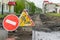 Road sign, detour, road repair on the background of the road and broken asphalt covering