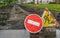 Road sign, detour, road repair on the background of the road and broken asphalt covering