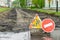 Road sign, detour, road repair on the background of the road and broken asphalt covering