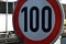 Road sign on a highway in the Czech Republic slightly dirty. indicates a speed limit of 100 km per hour. red circle with white cen