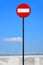 Road sign on a metal pole `Do not enter` sign against a blue sky with white clouds background.