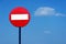 Road sign on a metal pole `Do not enter` sign against a blue sky with white clouds background.