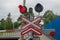 Road sign of railway crossing with double traffic light, shining red indicating approaching train, sound speakers, barrier lowered