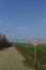 Road sign speed limit traffic 30 miles per hour standing on the side of the dirt road along the fields of green shoots