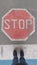 Road sign `Stop` painted on road with two standing feet in front