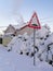 Road sign in suburbs and smoke from chimney of cottage in frosty winter