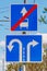 Road signs Direction of motion traffic on the lanes closeup against green trees and blue sky in sunny day