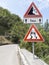 Road signs on a mountain road indicating landslide hazard and slippery asphalt