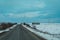 road between snowy fields with windmills in the background