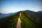 Road on spine and the top of the mountains covered with greenery with gentle valleys at dawn