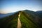 Road on spine and the top of the mountains covered with greenery with gentle valleys at dawn