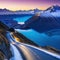 a road on a steep slope and the snow capped Lake Wakatipu Mount at sunset in New