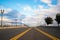 Road with street lights and dividing strip receding cloudy horizon