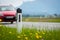 Road in the summer: reflector post, cars, flowers and green grass