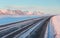 The road on a sunny winter day along the snow-capped mountains.