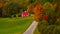 Road to a red scenic building surrounded by trees in forest in autumn