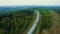 Road traffic, aerial view. Highway at forest with trees in spring. Cars and truck in motion on highway. Aerial above