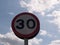 A road traffic sign with a sky background saying 30 speed limit