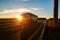 A road train carries a groupage cargo in a semi-trailer against the backdrop of a sunny sunset. Social transportation