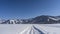 A road trampled by cars passes through an endless snow-covered valley.