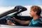 Road trip drive young man driver driving open roof convertible sports car on summer travel holiday vacation. Side
