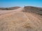 Road trip through rough dusty unpaved road with car tyre track through drought desert climate and rock mountain landscape