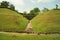 the road between two small hills full of green grass