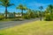 Road in vacation resort with green trees, grass and early sunlight