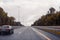 Road view through windshield car window with going rain drops during driving at speed. Unfocused highway. Autumn.