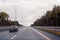 Road view through windshield car window with going rain drops during driving at speed. Unfocused highway. Autumn.