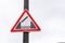 Road warning sign of drawbridge on a pole outside, gray and white thunderstorm sky on the background, close up