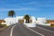 Road with white entry gate and palm trees