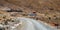 Road winding through arid mountains past farm