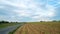 Road winding through the countryside along a freshly planted field and large cloudy sky