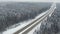 Road in the winter forest with driving cars. Aerial view. Vanishing point perspective.