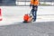 A road worker compacts asphalt with a gasoline vibratory compactor