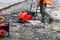 A road worker repairs and installs sewers on the road using a compactor plate and a petrol generator