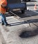 A road worker sprays a bitumen mixture onto the cleaned surface of the old asphalt for better adhesion to the new surface