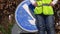 Road worker stands by road direction sign