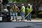 Road workers raking hot asphalt