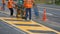 Road workers with thermoplastic spray road marking machine are working to paint traffic yellow lines