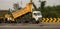Road works and construction of roads in India. Dump truck unloads the asphalt into asphalter paver, steam roller,