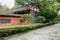 Roadside aged Chinese building with enclosure in trees and shrub