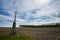 Roadside cross on plowed field.