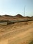 The roadside, highway with asphalt in the desert with sand, bumpers and lampposts, sand dunes, hills, mountains in a hot tropical